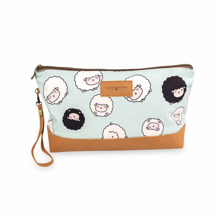 Front view of the Chubby Sheep Trinity Bag in seafoam green with cute cartoon white and black sheep print, tan vegan leather bottom, brown zipper, removable wrist strap, and Twice Sheared Sheep leather label