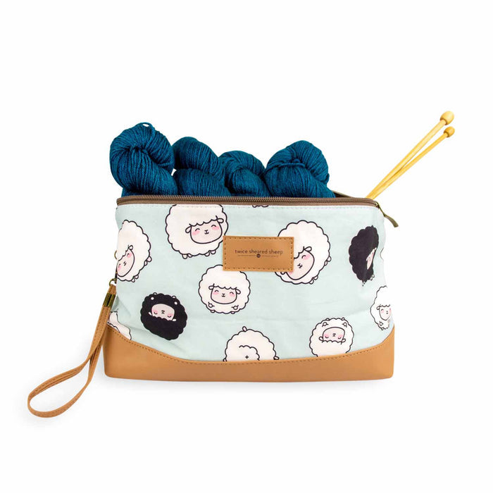 Chubby Sheep Trinity Bag shown open with teal yarn skeins and bamboo knitting needles tucked inside, demonstrating the bag's capacity for knitting projects