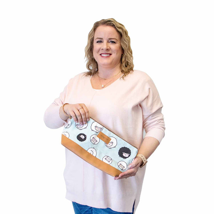 Model with blonde curly hair wearing a pink sweater, holding the Chubby Sheep Trinity Bag to show its medium size relative to the body