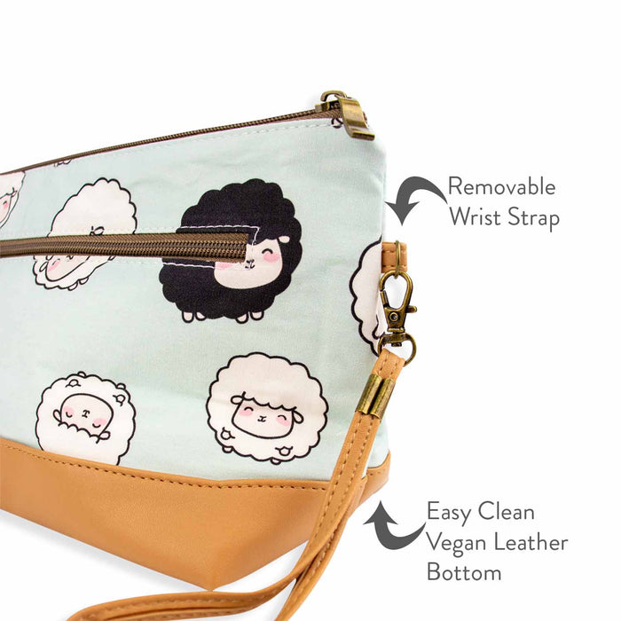 Close-up detail of the Chubby Sheep Trinity Bag corner showing the removable wrist strap with brass clasp and the easy-clean tan vegan leather bottom, with annotated text labels