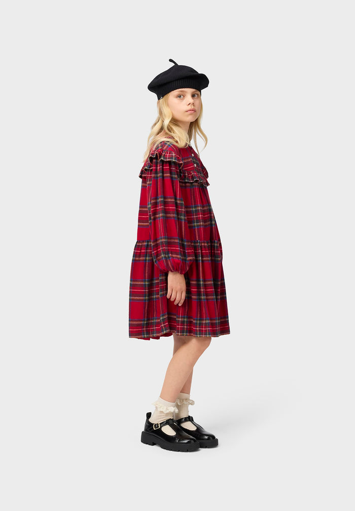 Person wearing a red plaid dress and black beret on a white background