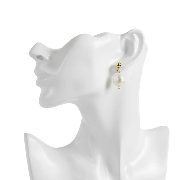 A high-resolution, side-profile shot of an elegant pearl drop earring featuring a polished gold stud and a large, lustrous white pearl, displayed on a sleek white mannequin bust against a pure white background.
