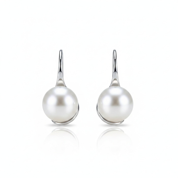 A high-resolution product shot of a pair of elegant pearl drop earrings featuring large, lustrous white pearls suspended from sleek silver-toned hooks, displayed against a pure white background with a soft reflection.