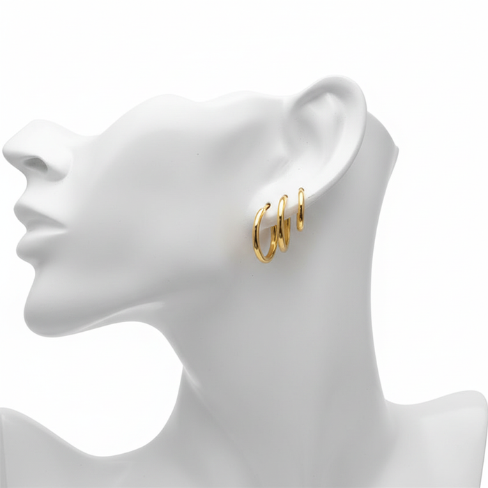 Set of three graduated gold-tone huggie hoop earrings with a high-polished finish, styled on a white mannequin profile to showcase a triple-pierced look.