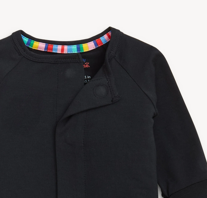 Close-up of a black baby long-sleeve top with a magnet button front and a colorful striped inner collar, shown on a light gray background.