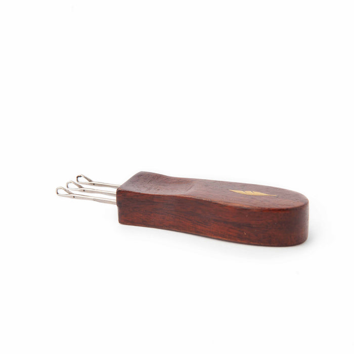 Cord Quill i-cord tool angled view showing dark wood handle thickness with gold feather inlay and metal prongs