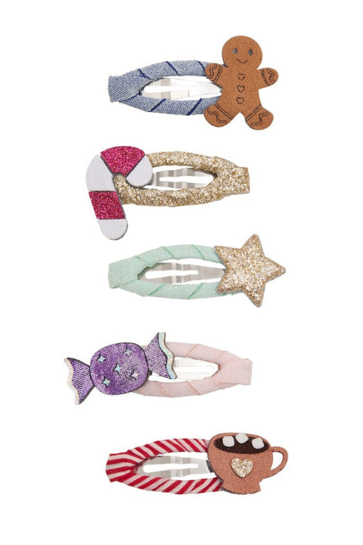 A set of five children's hair clips with holiday and candy-themed designs, including gingerbread, candy canes, a star, a wrapped candy, and a hot cocoa mug, shown on a plain white background.
