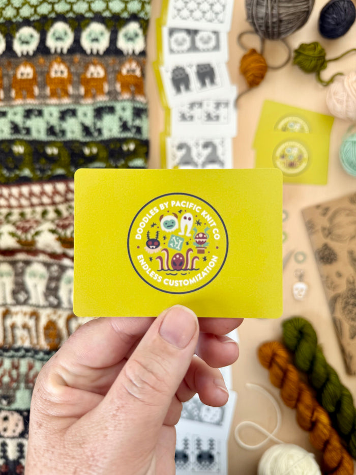 Hand holding the yellow Pacific Knit Co card back with the Doodles logo
