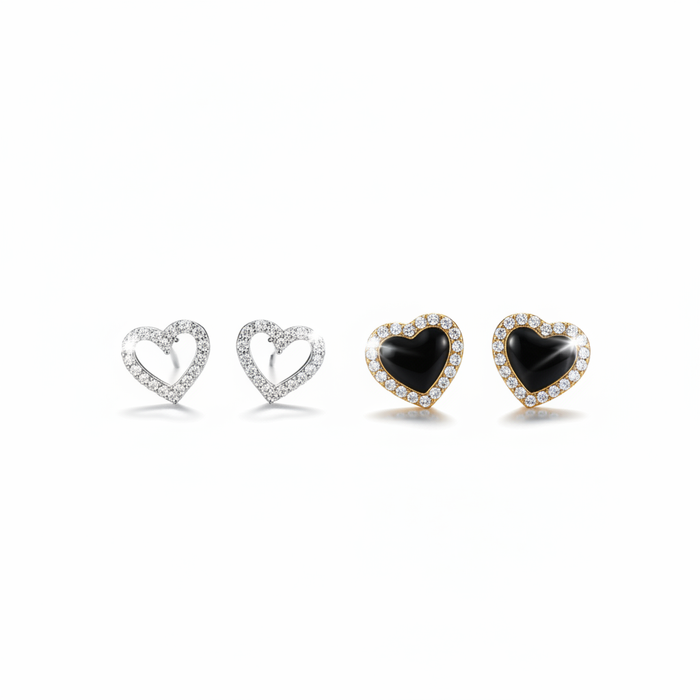 A high-resolution product shot featuring two pairs of heart-shaped stud earrings; one pair is silver with an open-heart design encrusted in sparkling crystals, and the other is gold-toned with a solid black onyx-style center surrounded by a crystal halo, both displayed against a pure white background.