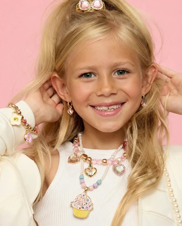 Young girl wearing colorful jewelry against a pink background
