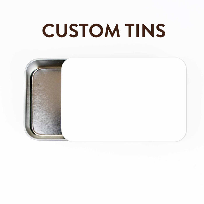 Custom Tins title graphic showing a large sliding-lid metal storage tin partially open with a blank white customizable sticker on the lid