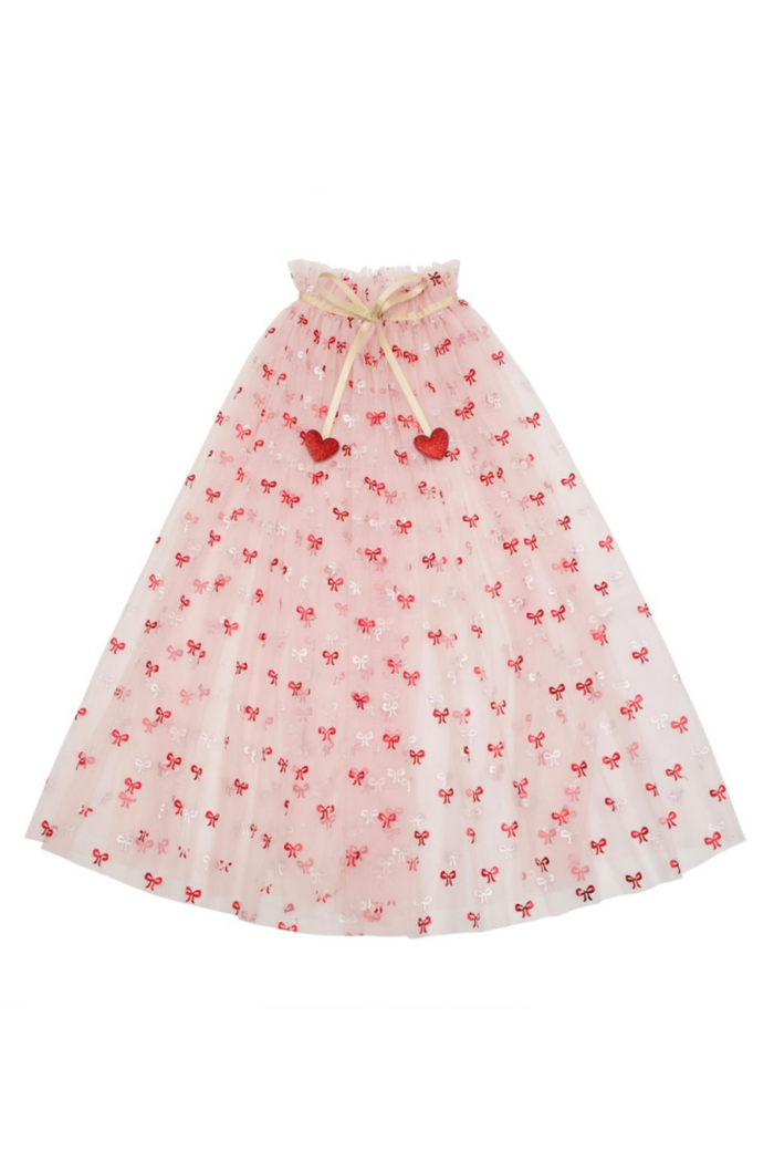 A pink tulle cape with a red bow pattern and hearts at the neck, displayed against a plain white background.