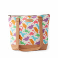 Dino Mega Trinity Bag front view showing colorful dinosaur silhouettes in pink, orange, purple, blue, and green on white cotton canvas with tan vegan leather bottom, straps, and Twice Sheared Sheep label