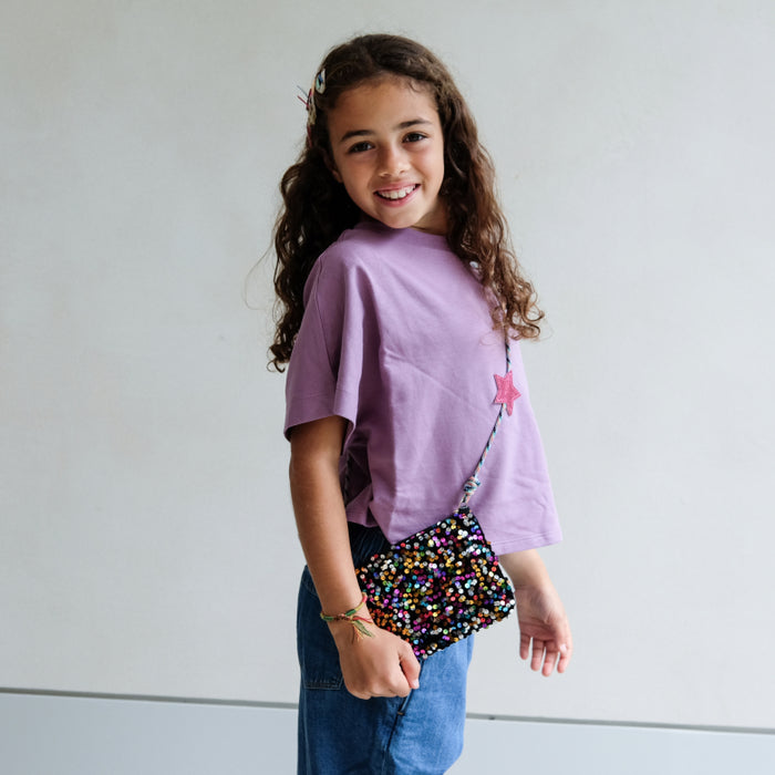 Young girl wearing a sparkly crossbody purse.