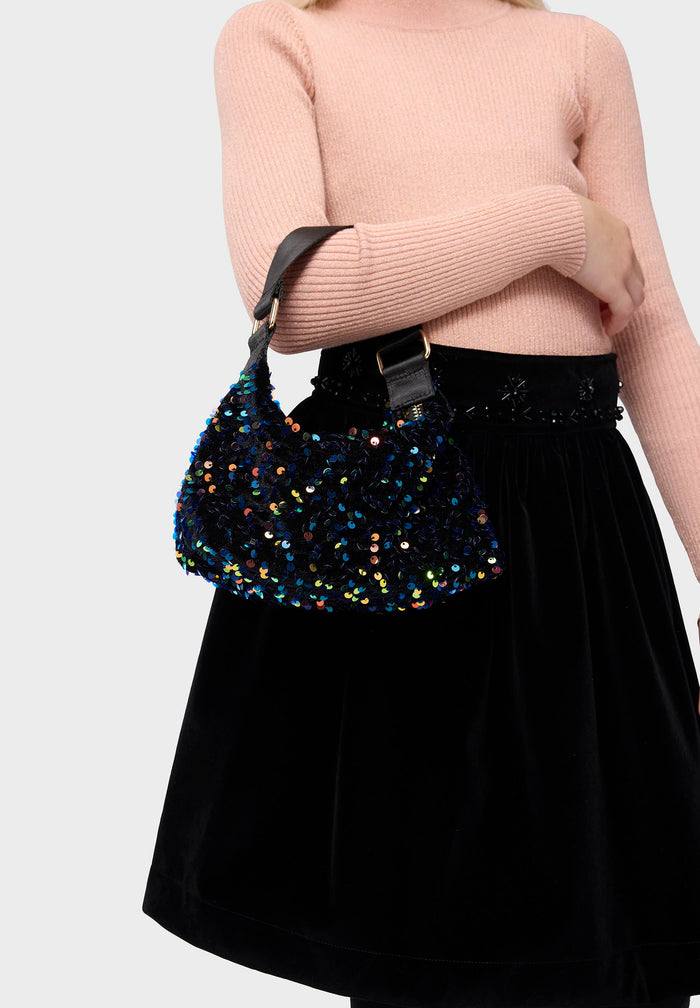 Person wearing a sequined handbag with a plain background