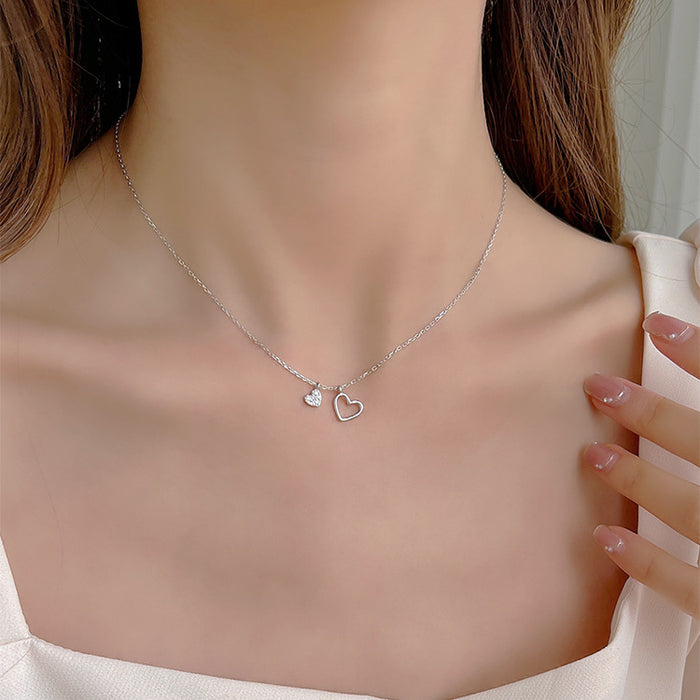 Minimalist two-tone necklace with one small and one medium heart pendant hanging together on a dainty gold chain.