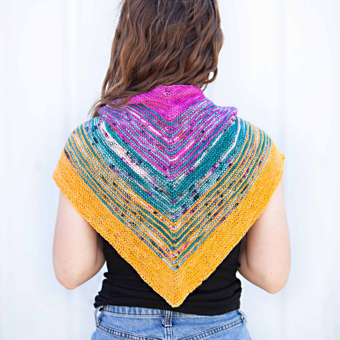Person wearing a colorful triangular shawl on a white background