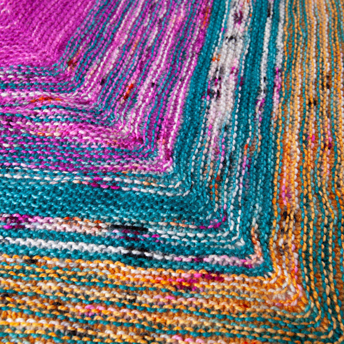 Close-up detail of the Down By The Sea shawl garter stitch texture where magenta, teal, and golden orange stripes meet at the chevron point