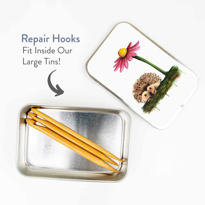 Duo wooden repair hooks stored inside an open Twice Sheared Sheep hedgehog tin showing the hooks fit inside the large tin size