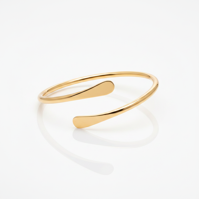 A minimalist 18k gold-dipped open bangle featuring a fluid, tapered wrap design with a polished finish, crafted from tarnish-resistant titanium steel for a modern "Liquid Metal" editorial aesthetic.