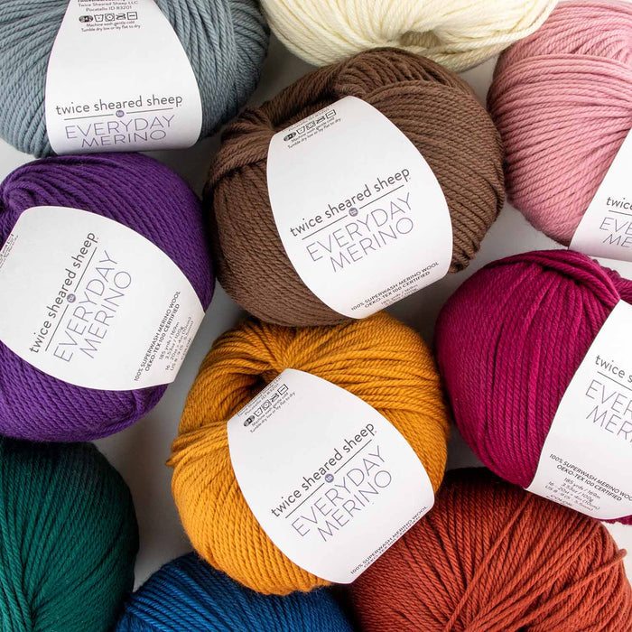 Collection of Everyday Merino worsted weight superwash merino yarn skeins in assorted colors including orange, red, purple, pink, teal, dove gray, and natural