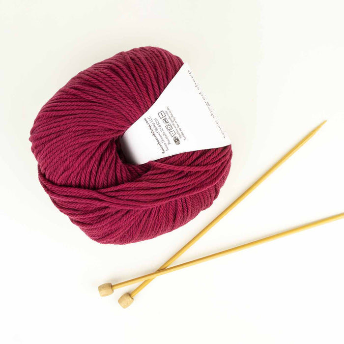 Ball of Everyday Merino worsted weight yarn in Sugar Beet (deep pink) with white Twice Sheared Sheep label on gray background