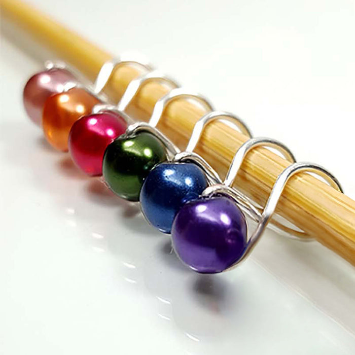 Rainbow pearl infinity ring stitch markers in orange, pink, green, blue, and purple on bamboo knitting needle
