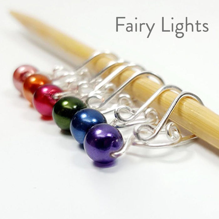 Rainbow pearl melody ring removable stitch markers in pink, green, blue, and purple with silver hooks on bamboo needle