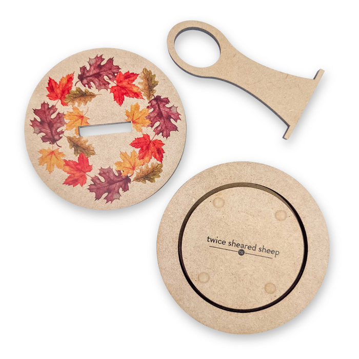 Fall Leaves Carousel shown disassembled: printed autumn leaf lid, yarn guide, and Twice Sheared Sheep engraved wooden base