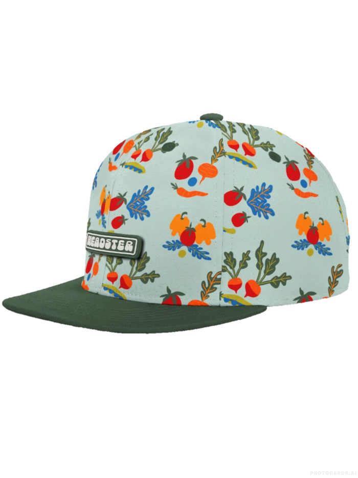 A snapback cap by Headster featuring a light mint green front panel with a colorful fruit and vegetable print, contrasted with a dark forest green flat brim and a black Headster logo patch on the front.