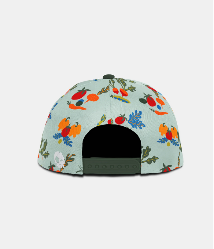 The back of a structured snapback cap featuring a light mint green background with a colorful, dense botanical and fruit pattern, finished with an olive green adjustable strap and button.