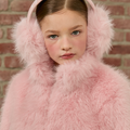 Person wearing a pink fluffy earmuffs against a brick wall