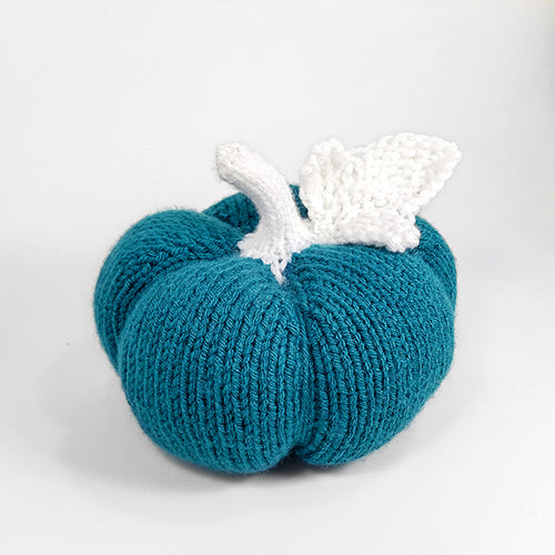 Teal ribbed-knit pumpkin with white knitted stem and leaf showing the stockinette rib texture from the front