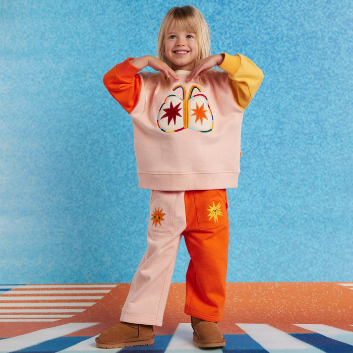 Child wearing a colorful outfit with a heart shape on a blue background