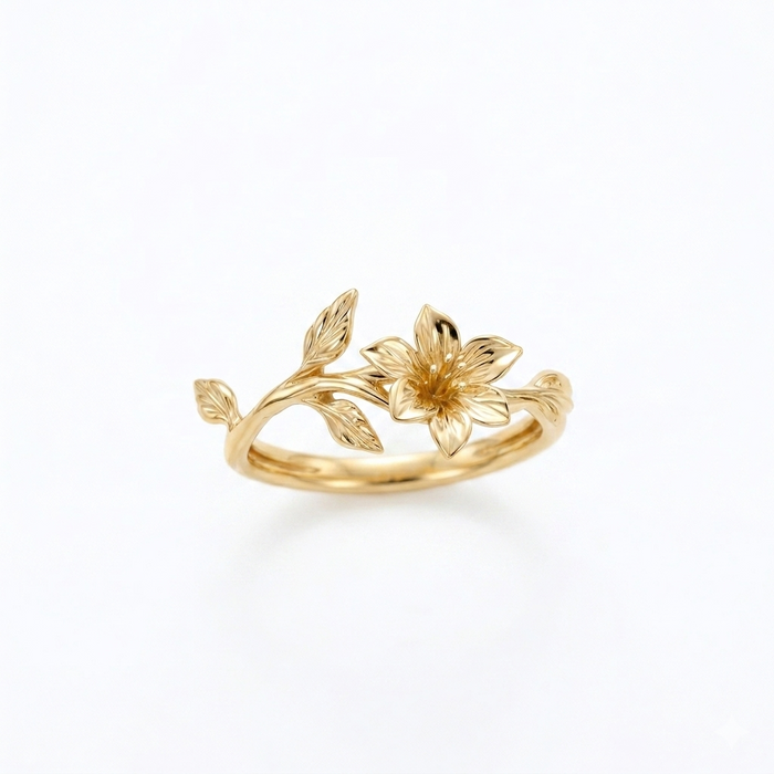 A delicate yellow gold ring with a single sculpted lily flower and an organic vine of leaves, set against a seamless white background.