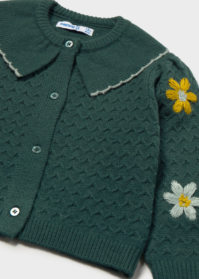 Green knitted cardigan with embroidered flowers on a white background