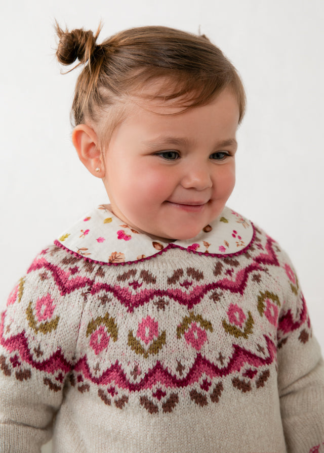 Child wearing a patterned sweater with a white background