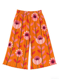 Bright orange pleated wide-leg pants featuring a retro floral and leaf pattern in pink, red, and purple, displayed flat against a white background.