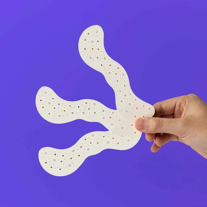 Hand holding a white, textured object against a purple background