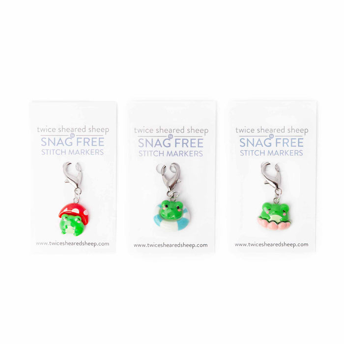 Three frog clip stitch markers displayed on Twice Sheared Sheep Snag Free branded cards featuring a mushroom hat frog, a pool float frog, and a lily pad frog with lobster clasp closures