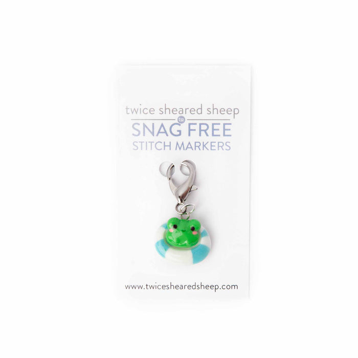 Close-up of pool float frog clip stitch marker on Twice Sheared Sheep Snag Free branded card showing the green kawaii frog sitting in a blue and white striped pool ring with lobster clasp