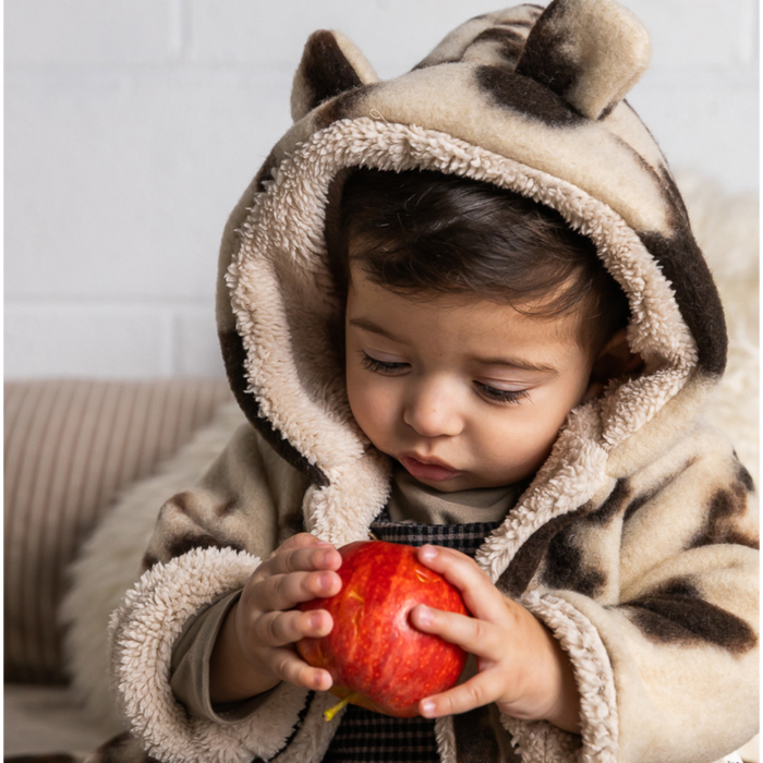 Child in a furry coat holding an apple