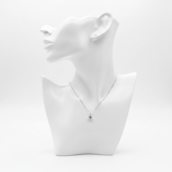 A delicate silver-toned necklace featuring a small sunflower-shaped pendant with a dark center, displayed on a minimalist white mannequin bust.