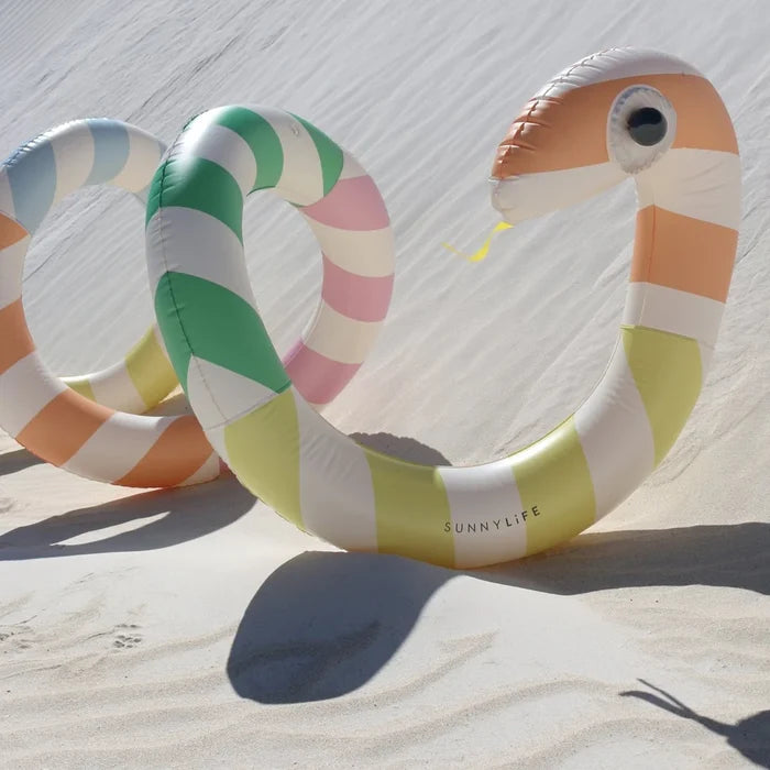 Colorful inflatable snake-shaped pool toy on sand with 'Sunnylife' branding.
