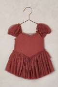 Red dress with ruffled sleeves on a hanger against a beige background