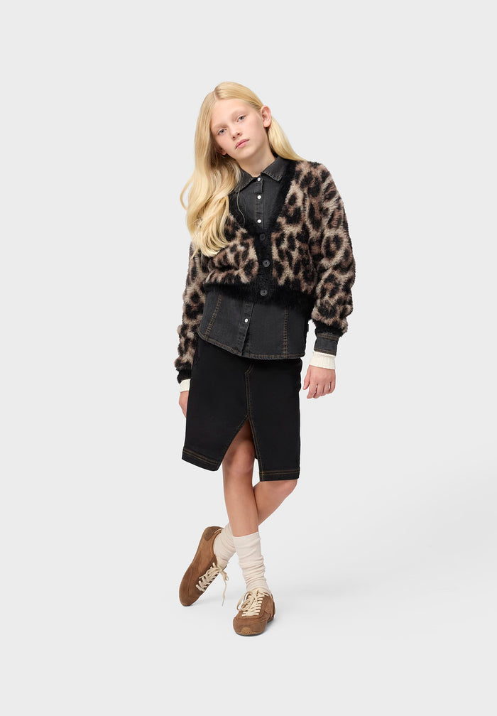 Person wearing a leopard print cardigan over a black shirt and skirt on a white background