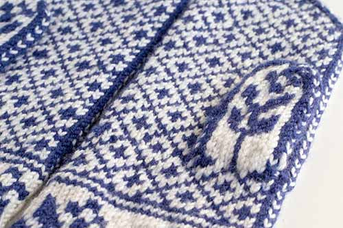 Close-up detail of the Gnomes in Love mitten showing the navy and white stranded colorwork gnome motif and seed stitch texture