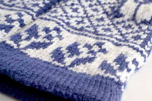 Close-up of blue and white stranded colorwork on Gnomes in Love mittens showing the gnome motif pattern with snowflake accents and ribbed cuff