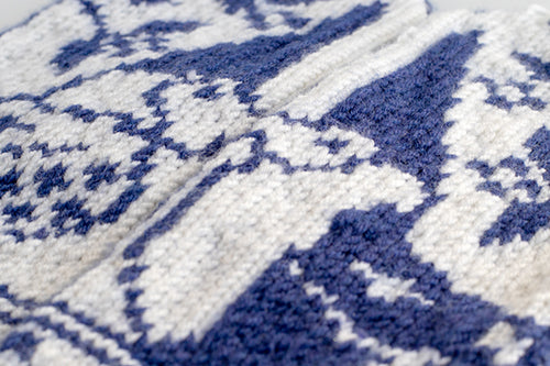 Detail of blue and white colorwork gnome figures knitted into the Gnomes in Love mitten, showing two gnomes facing each other with a heart between them