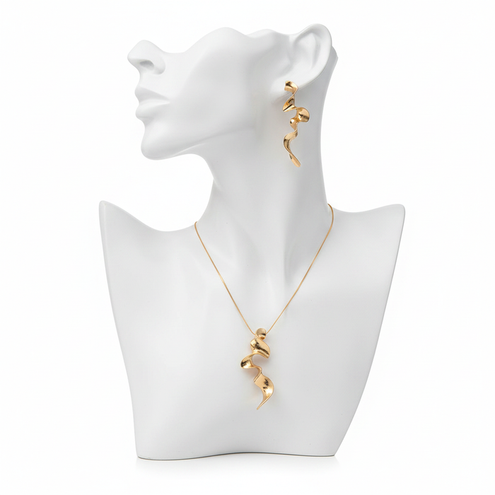 A luxury gold-toned jewelry set featuring a sculptural wavy pendant and matching spiral drop earrings on a minimalist white mannequin bust.